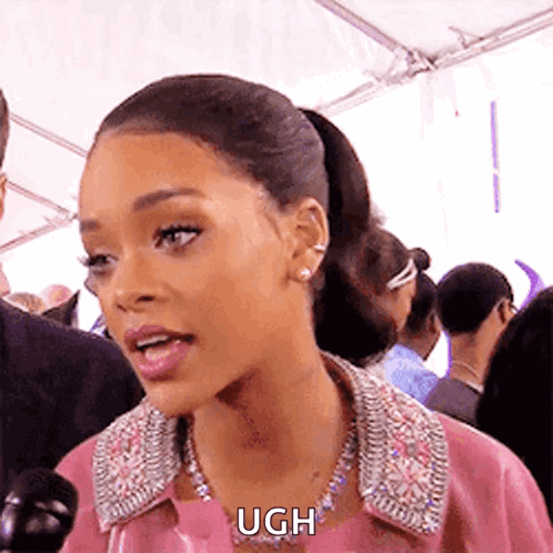 A Woman Wearing A Pink Jacket And A Necklace Is Talking Into A Microphone And Says Ugh . GIF
