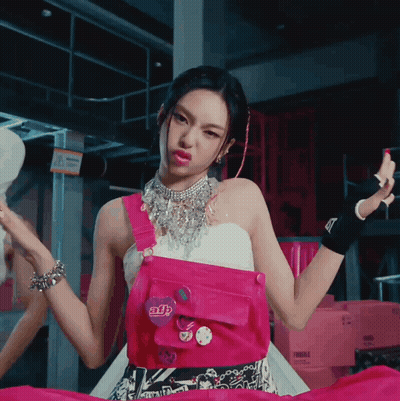 A Woman Wearing A Pink Overalls And A Necklace With A Button That Says Adb GIF