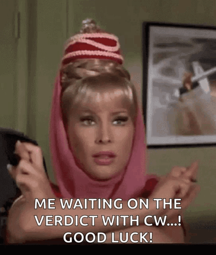 A Woman Wearing A Pink Scarf And A Red Hat Is Waiting On The Verdict With Good Luck . GIF