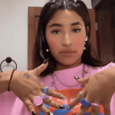 A Woman Wearing A Pink Shirt And A Bunch Of Rings On Her Hands . GIF