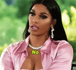 A Woman Wearing A Pink Shirt And A Necklace With The Word No On It Is Sitting In A Chair . GIF