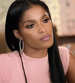 A Woman Wearing A Pink Shirt And Hoop Earrings Is Making A Serious Face . GIF