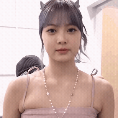 A Woman Wearing A Pink Tank Top And Pearl Necklace GIF
