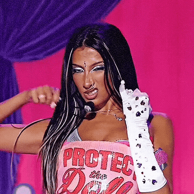 A Woman Wearing A Pink Top That Says Protec The Doll GIF