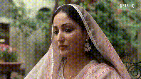 A Woman Wearing A Pink Veil And Earrings Is Looking At Something . GIF