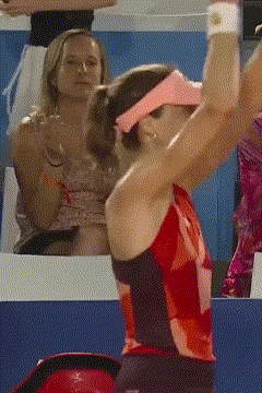 A Woman Wearing A Pink Visor And A Red Top Is Serving A Tennis Ball GIF