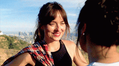 A Woman Wearing A Plaid Scarf Is Smiling At Another Woman GIF