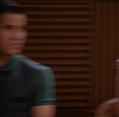 A Woman Wearing A Plaid Shirt And A Scarf Looks At The Camera GIF