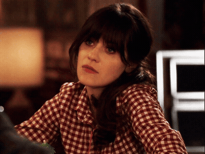 A Woman Wearing A Plaid Shirt Is Looking At Something GIF