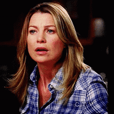 A Woman Wearing A Plaid Shirt Is Making A Surprised Face . GIF