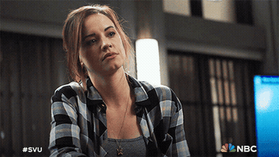 A Woman Wearing A Plaid Shirt Is Sitting In Front Of A Nbc Logo GIF
