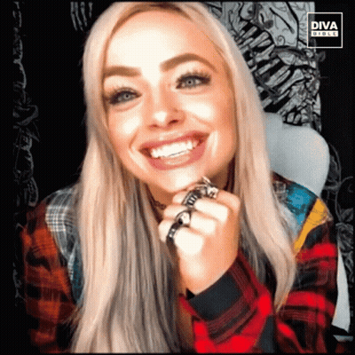 A Woman Wearing A Plaid Shirt Is Smiling With The Diva Girls Logo Behind Her GIF