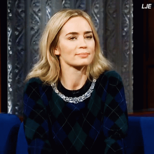 A Woman Wearing A Plaid Sweater Is Sitting In A Blue Chair And The Letters Lje Are On The Bottom Right GIF
