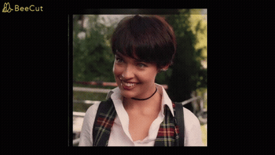 A Woman Wearing A Plaid Vest And A Choker Smiles In A Beecut Ad GIF