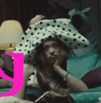 A Woman Wearing A Polka Dot Hat Is Laying On A Bed . GIF