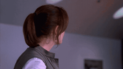 A Woman Wearing A Ponytail And Earrings Looks To The Side GIF
