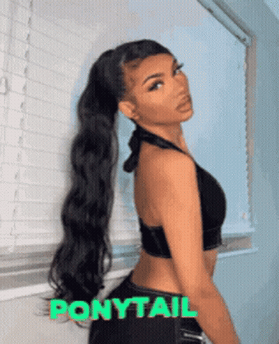 A Woman Wearing A Ponytail Stands In Front Of A Window GIF