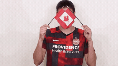 A Woman Wearing A Providence Health And Services Jersey Holds A Canadian Flag GIF