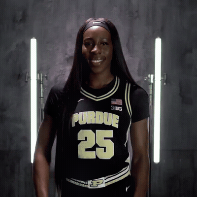 A Woman Wearing A Purdue Jersey Number 25 Smiles For The Camera GIF
