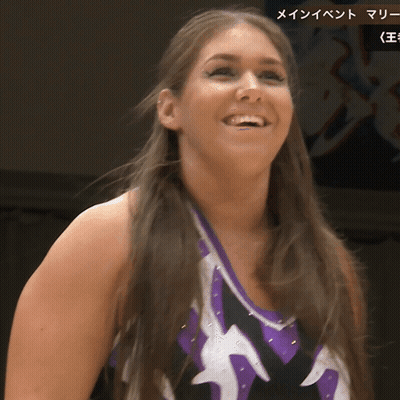 A Woman Wearing A Purple And White Top Smiles For The Camera GIF