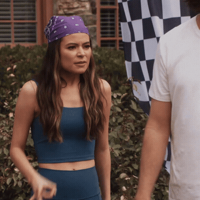 a woman wearing a purple bandana stands next to a man in front of a checkered flag