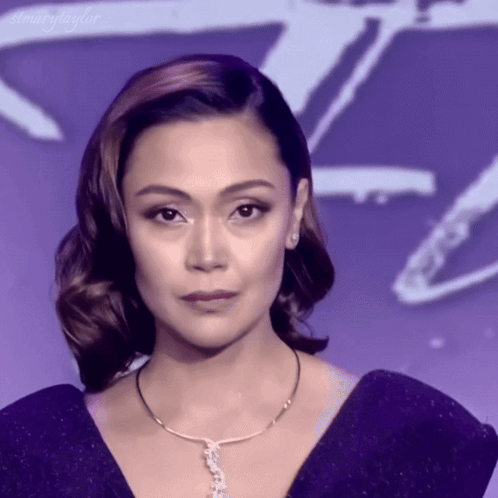 A Woman Wearing A Purple Dress And A Necklace With The Word Taylor On It GIF