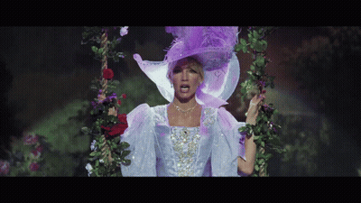 A Woman Wearing A Purple Hat And A White Dress Is Standing On A Swing GIF