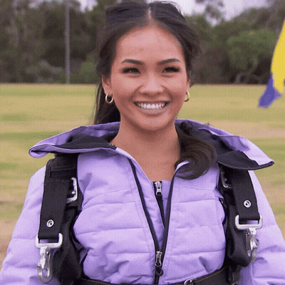 A Woman Wearing A Purple Jacket And A Black Harness Smiles GIF