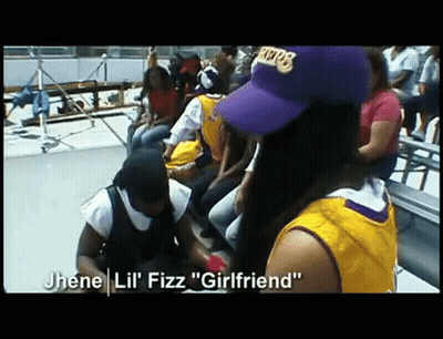 A Woman Wearing A Purple Lakers Hat Sits In A Crowd Of People GIF