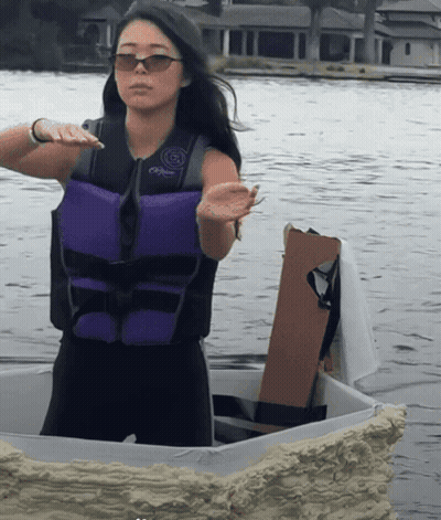 A Woman Wearing A Purple Life Vest And Sunglasses Stands In The Water GIF