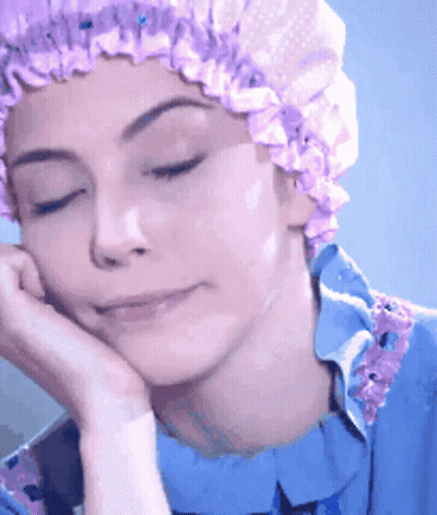 A Woman Wearing A Purple Shower Cap Rests Her Hand On Her Face GIF