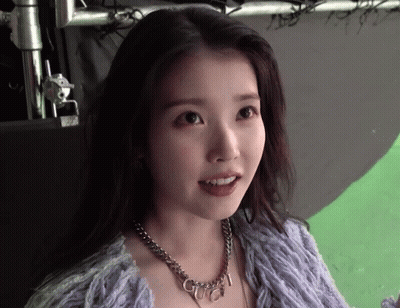 A Woman Wearing A Purple Sweater And A Necklace With The Word Gucci On It GIF