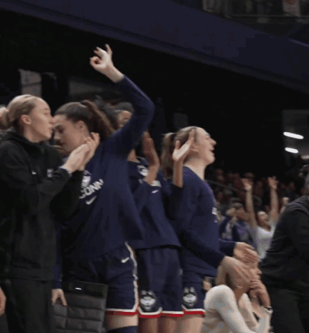 A Woman Wearing A Purple Uconn Jersey Applauds Her Teammates GIF