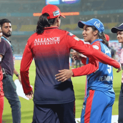 A Woman Wearing A Red Alliance University Jersey Is Hugging Another Woman GIF