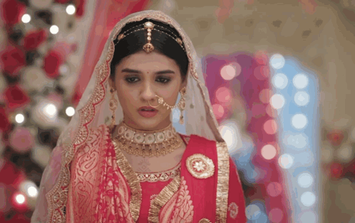 A Woman Wearing A Red And Gold Dress And Veil GIF