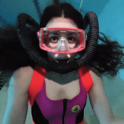 A Woman Wearing A Red And Purple Swimsuit Is Swimming GIF
