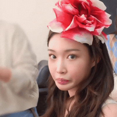A Woman Wearing A Red And White Flower On Her Head Making A Face GIF