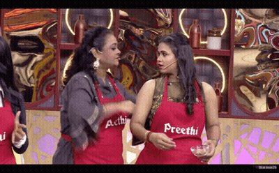 A Woman Wearing A Red Apron That Says Precthi Talks To Another Woman GIF