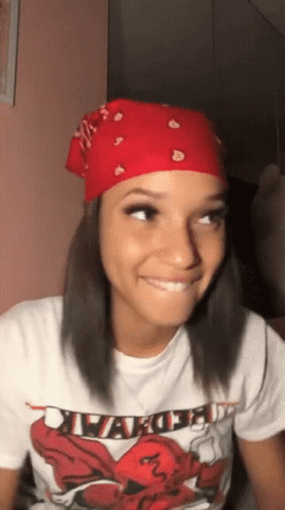 A Woman Wearing A Red Bandana And A White T-Shirt Is Smiling And Looking Up . GIF