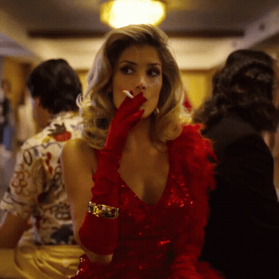 A Woman Wearing A Red Dress And Red Gloves Is Smoking A Cigarette GIF