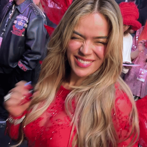A Woman Wearing A Red Dress Is Smiling And Making A Funny Face . GIF