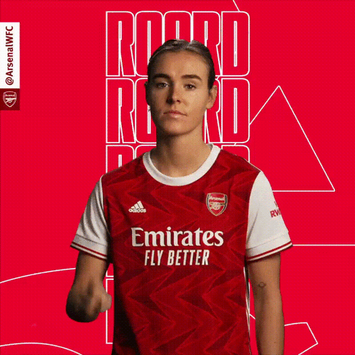 A Woman Wearing A Red Emirates Fly Better Jersey Is Giving A Peace Sign GIF