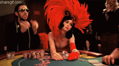 A Woman Wearing A Red Feathered Headdress Is Playing Poker GIF