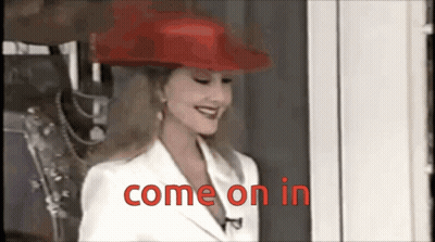 A Woman Wearing A Red Hat And White Jacket Says Come On In GIF