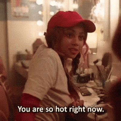 A Woman Wearing A Red Hat Is Sitting At A Desk And Says You Are So Hot Right Now . GIF