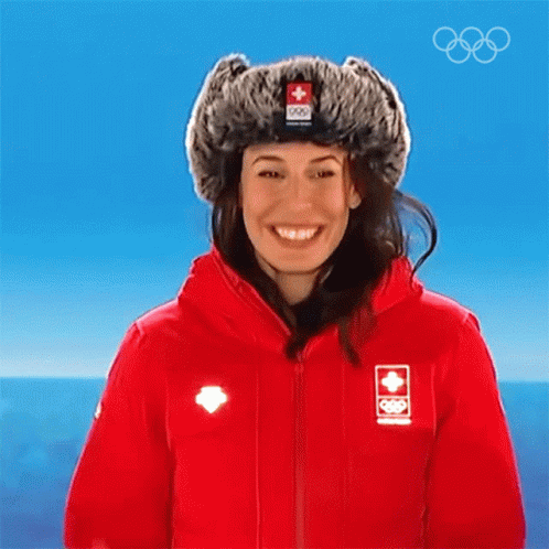 A Woman Wearing A Red Jacket And A Fur Hat With A Swiss Flag On It GIF
