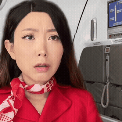 A Woman Wearing A Red Jacket And A Scarf Is Looking At The Camera GIF