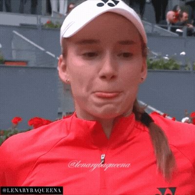 A Woman Wearing A Red Jacket And A White Yonex Hat With The Name Lenarybaqueena On The Bottom GIF