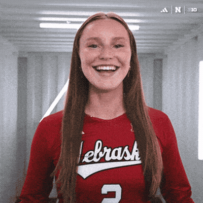 A Woman Wearing A Red Lebrask Jersey Smiles For The Camera GIF
