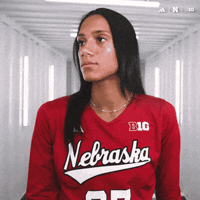 A Woman Wearing A Red Nebraska Jersey Looks To The Side GIF